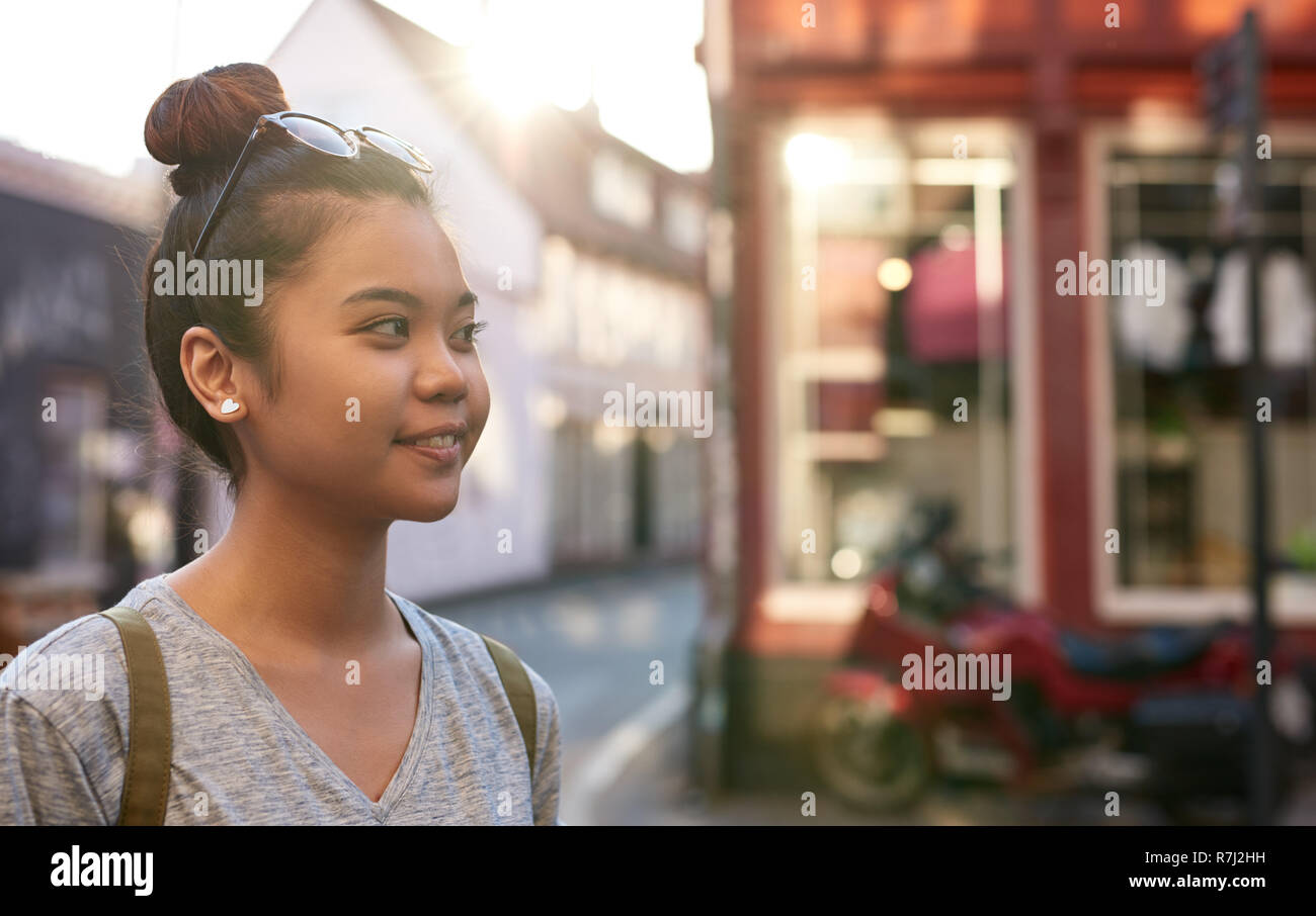 Giovane donna asiatica sorridere mentre passeggiate in città Foto Stock