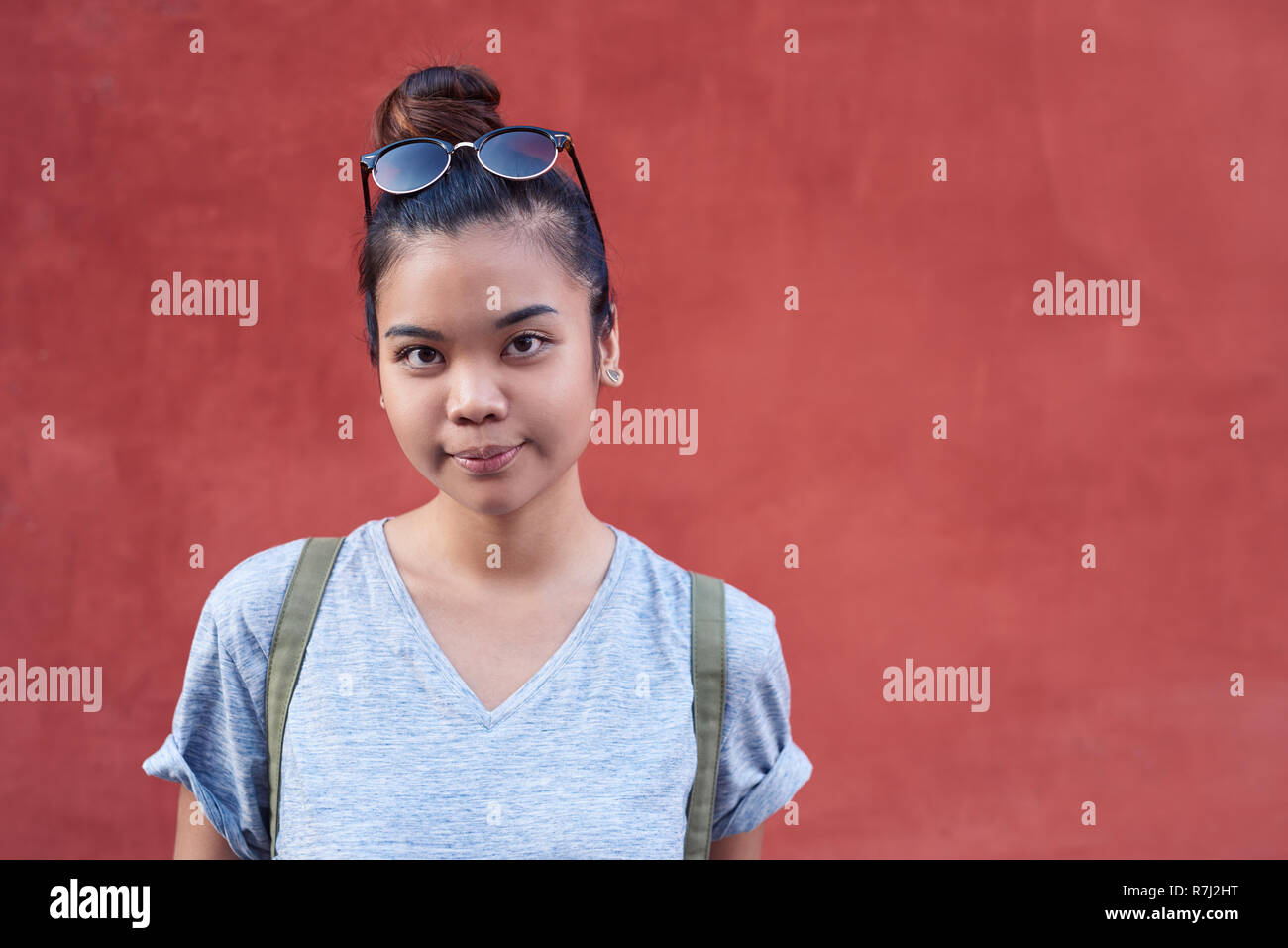 Giovane donna asiatica sorridere mentre in piedi da una parete al di fuori Foto Stock