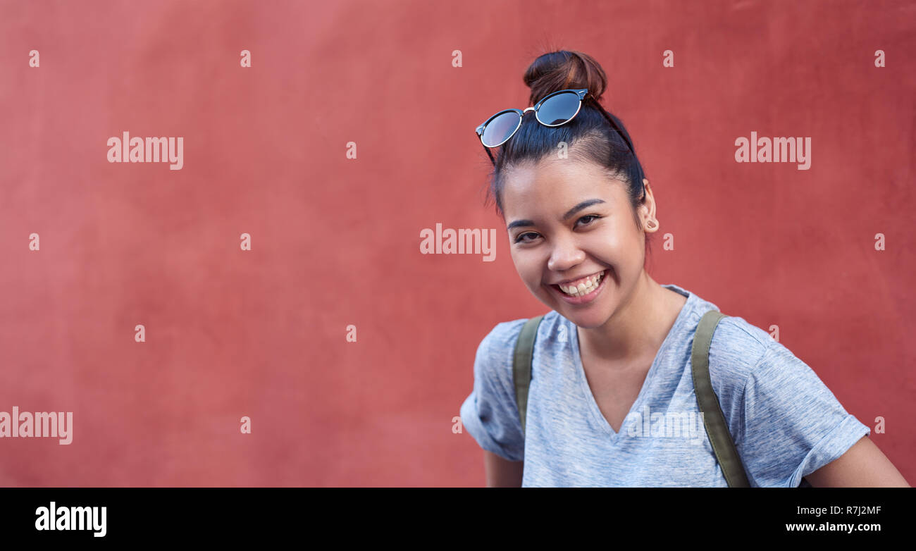 Giovane donna asiatica di ridere di fronte a un muro esterno Foto Stock