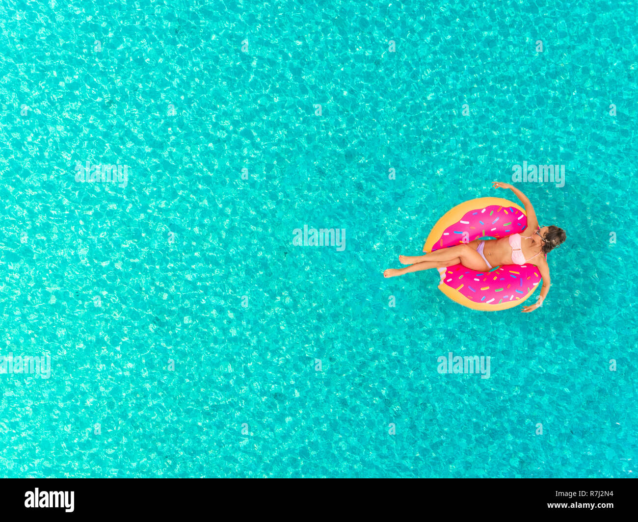 Vista aerea della donna sul galleggiante gonfiabile a forma di ciambella materasso, rilassante sul mare trasparente. Foto Stock