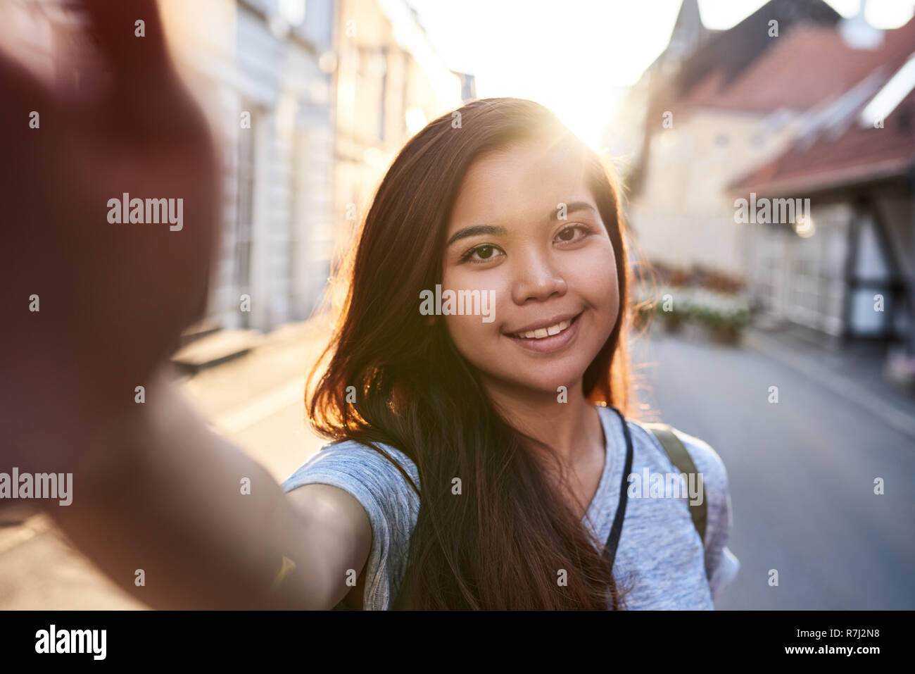 Sorridente donna asiatica tenendo selfies mentre passeggiando per la città Foto Stock