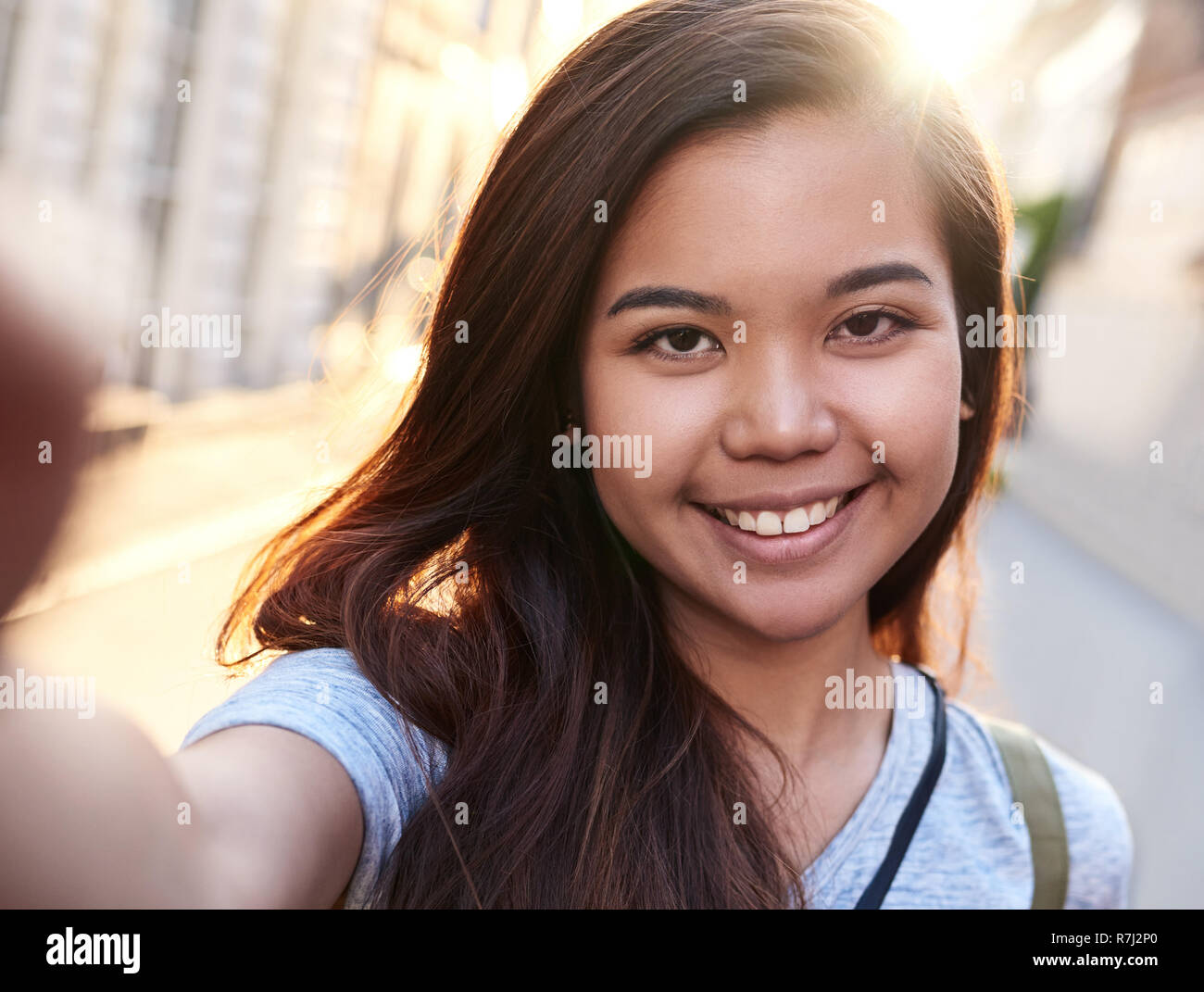 Contenuto giovane donna asiatica a piedi nella città prendendo selfies Foto Stock
