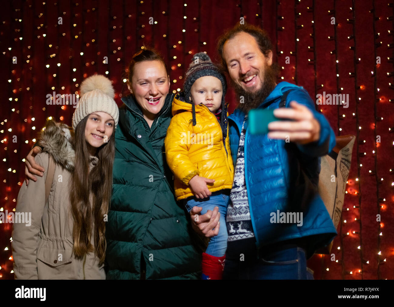 Padre tenendo selfie con la famiglia al mercato di Natale. Foto Stock