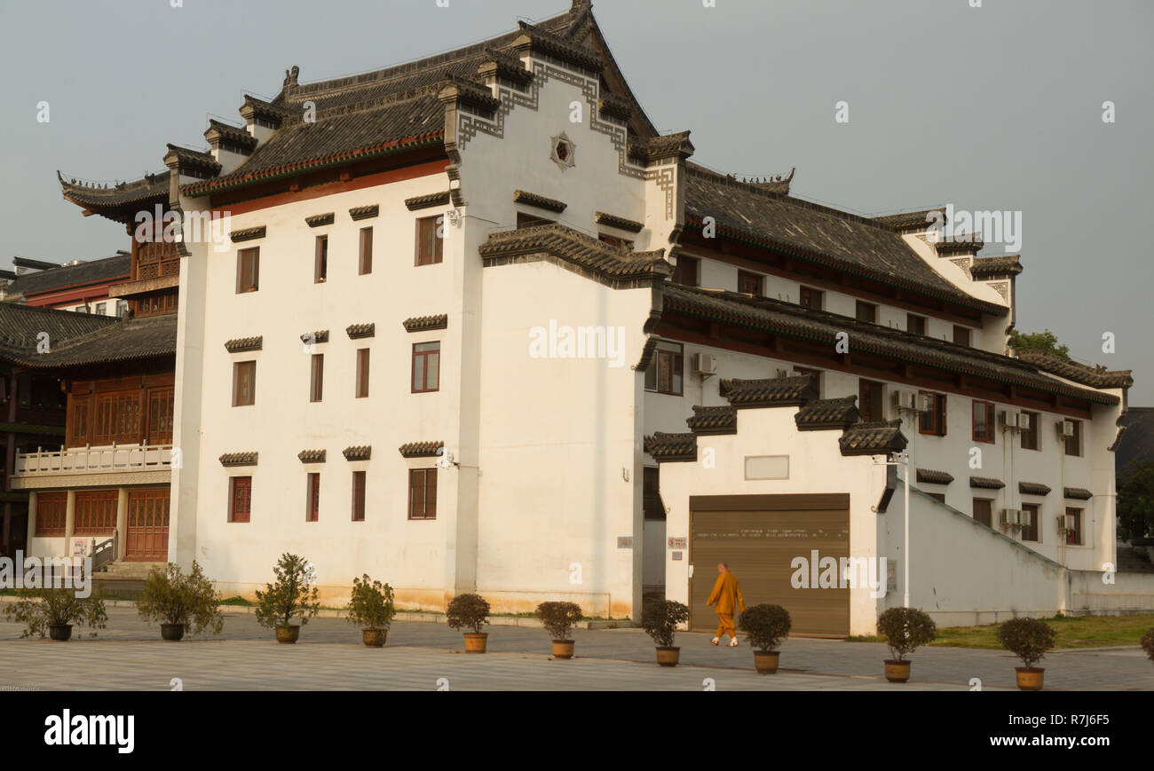 Un monaco buddista in arancione vesti a piedi nella parte anteriore del Guiyuan tempio buddista a Wuhan, Cina. Foto Stock Un monaco buddista in arancione vesti a piedi nella parte anteriore del Guiyuan tempio buddista a Wuhan, Cina. Foto Stock