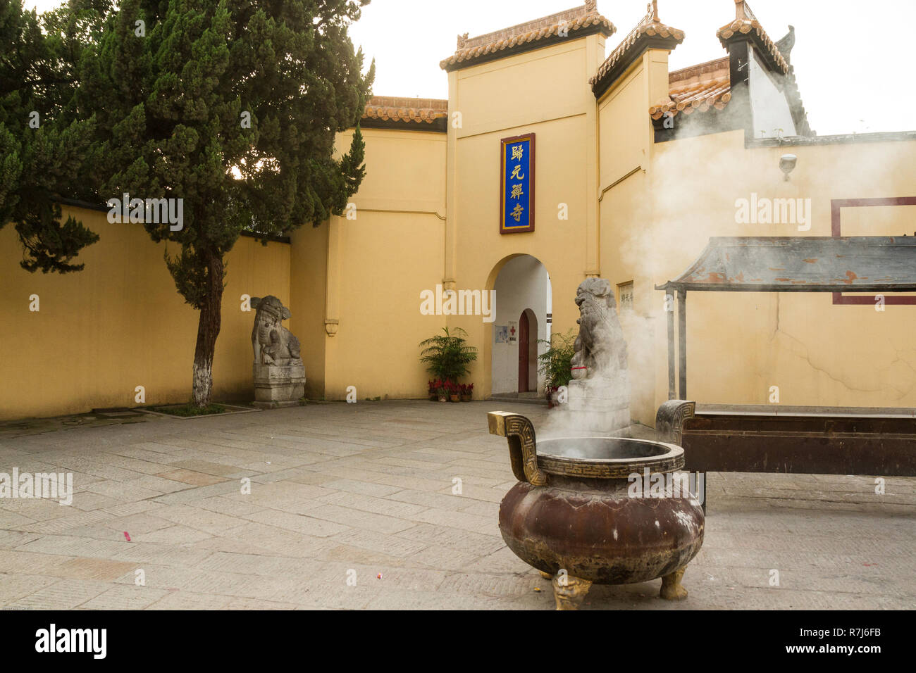 Guiyuan tempio buddista, Wuhan, Cina. Un grande bronzo incensiere con il fumo si diffonde fino è nella parte anteriore del tempio. Foto Stock Guiyuan tempio buddista, Wuhan, Cina. Un grande bronzo incensiere con il fumo si diffonde fino è nella parte anteriore del tempio. Foto Stock