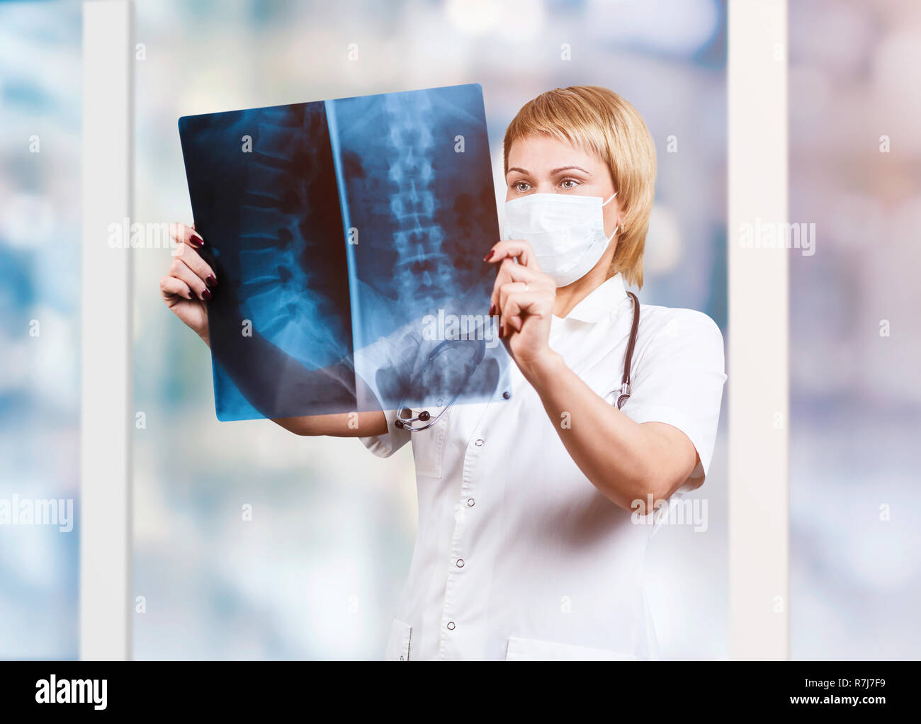 Medico donna guardando un x-ray della colonna vertebrale. Su sfondo sfocato. Foto Stock