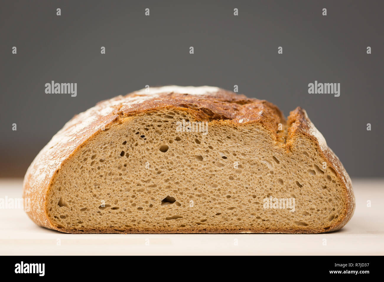 Un tipico tedesco della pagnotta di pane di segale con la superficie incisa rivolta a th viewer giacente su di un legno di tavolo di faggio. Closeup shot. Foto Stock