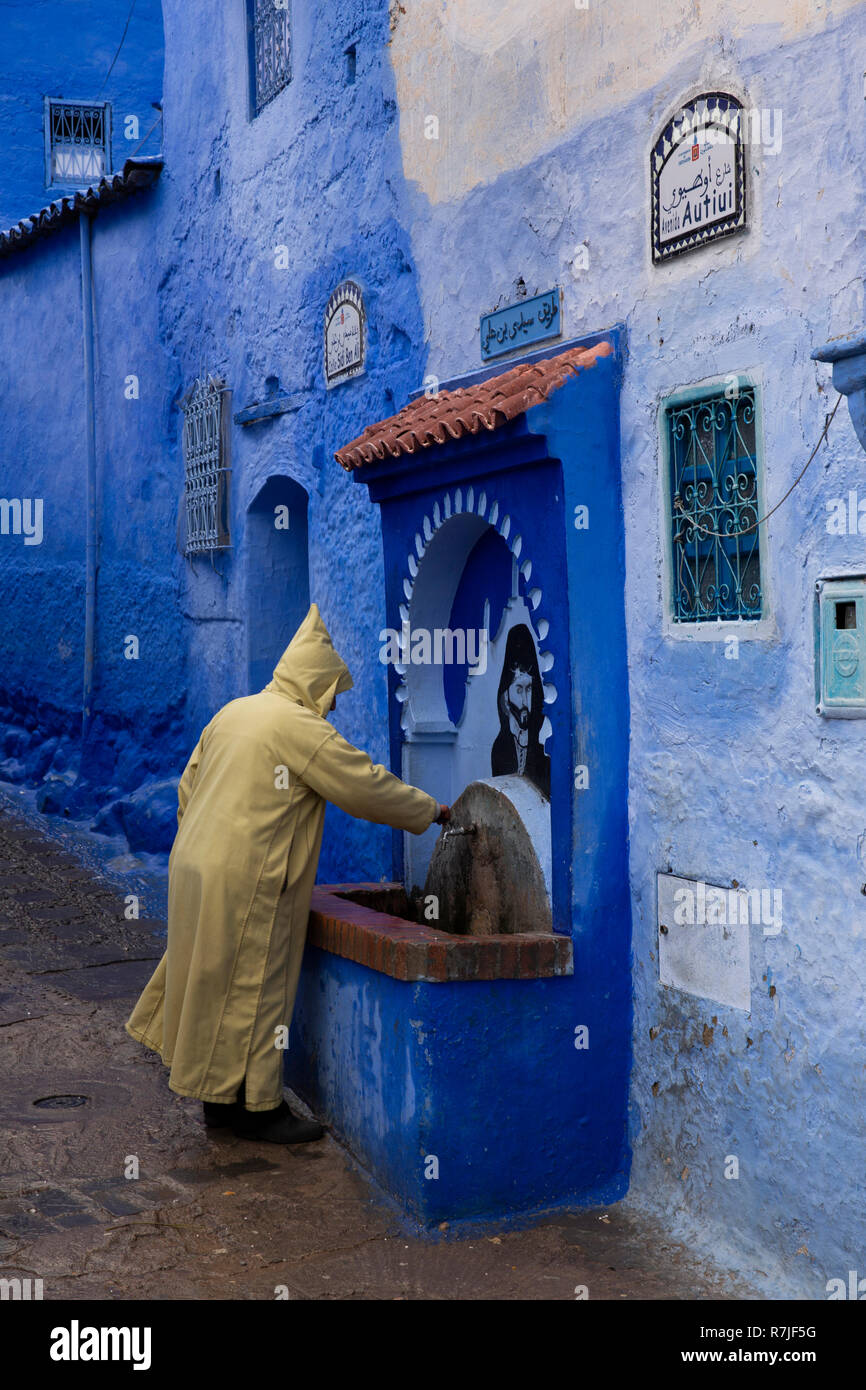 Mc457 Marocco, Chefchaouen, Medina, Avenida Autiui, uomo in Djellaba al tradizionale fontana di acqua Foto Stock