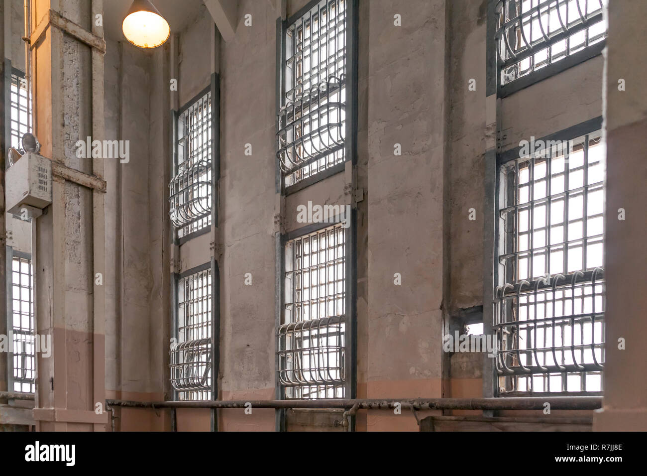 Vecchio penitenziario di correzzione jailhouse parete multilivello di windows coperto con acciaio solido verticali e barre orizzontali dipinte in toni neutrali. Foto Stock