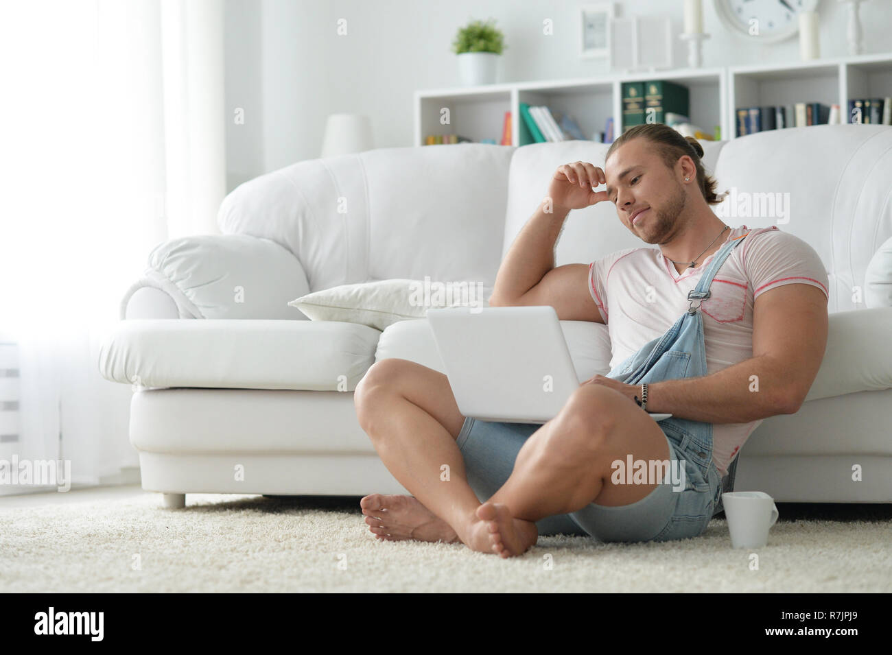 Ritratto di giovane uomo parigamba trascorrendo del tempo con il portatile a casa Foto Stock