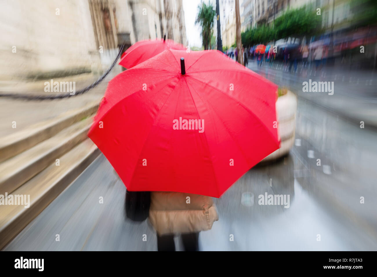 Persona con ombrellone rosso nella città di pioggia con telecamera di fatto l'effetto zoom. Foto Stock