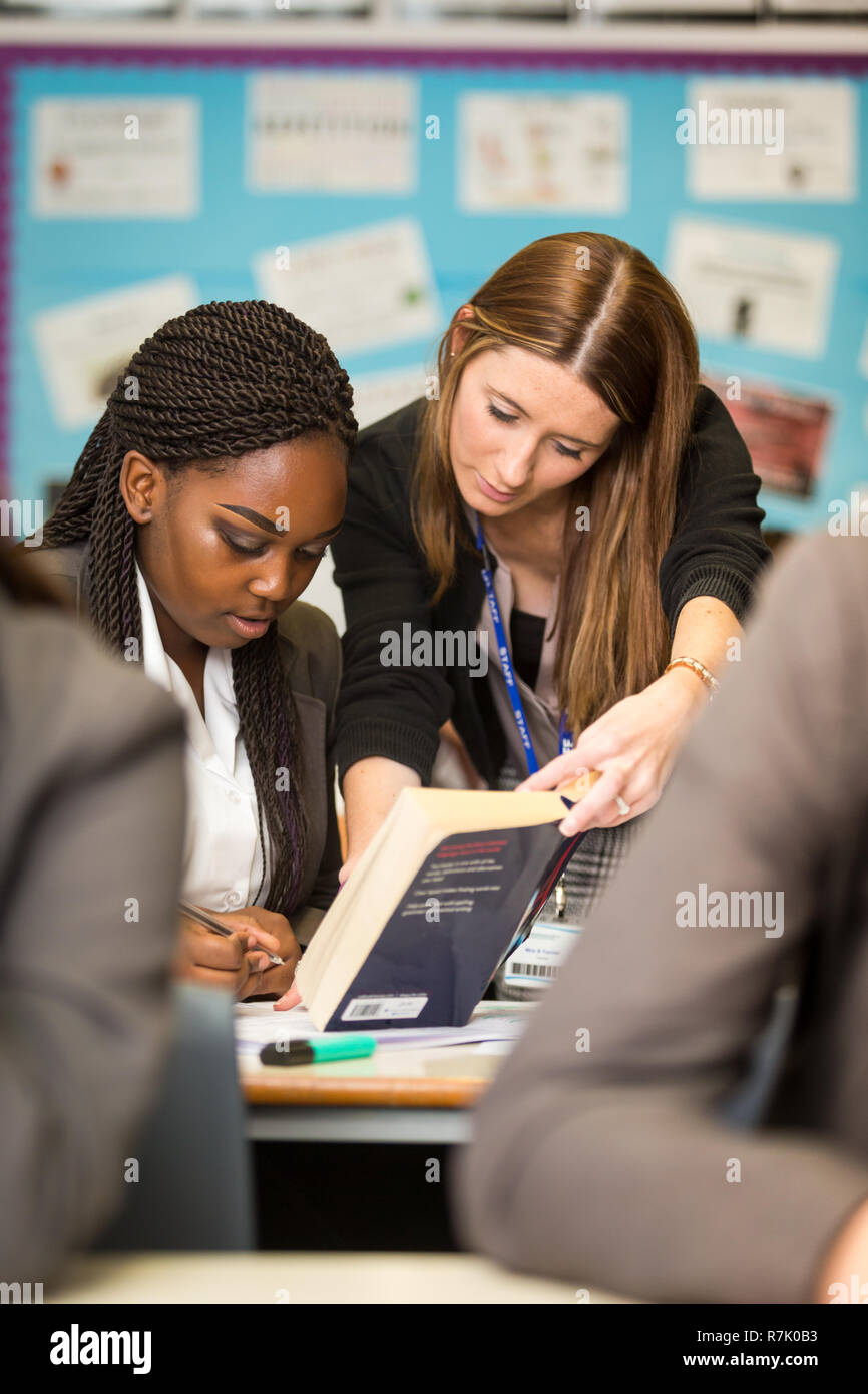 Insegnante di bianco aiutando un nero minoranza etnica schoolgirl in un REGNO UNITO British school Foto Stock