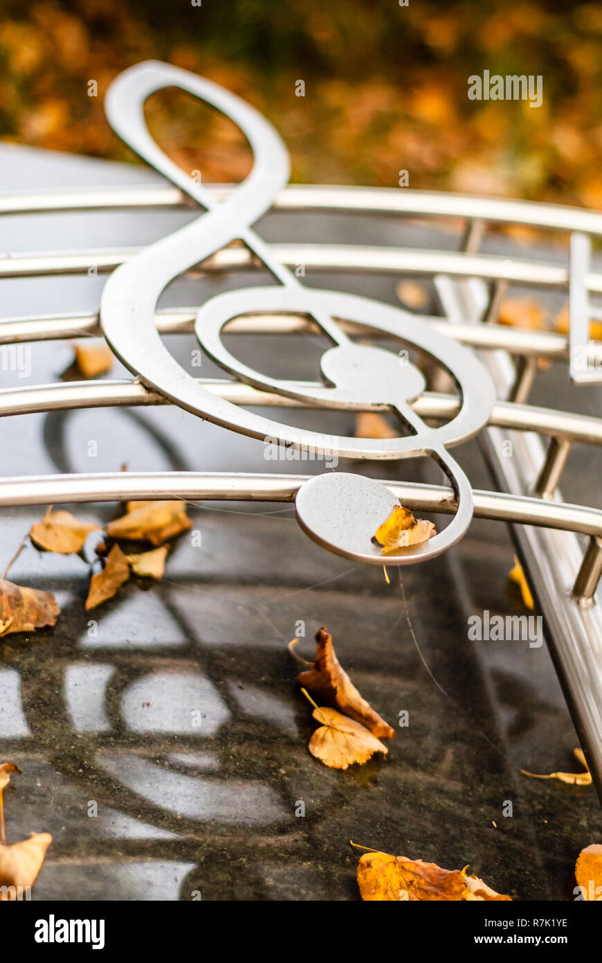 Silver Chrome clef con music bar su un monumento con foglie di autunno Foto Stock