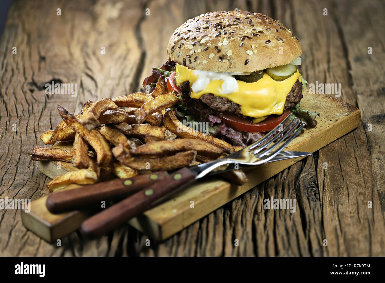 In casa cheeseburger e patatine fritte sul rustico sfondo di legno Foto Stock
