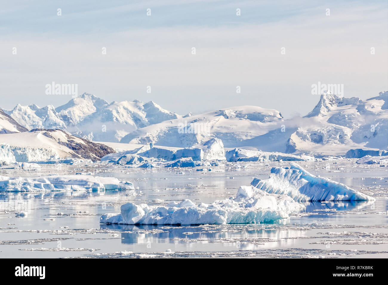 Iceberg sulle tranquille acque della baia Neko con montagne innevate e il ghiacciaio in background, Antartide Foto Stock