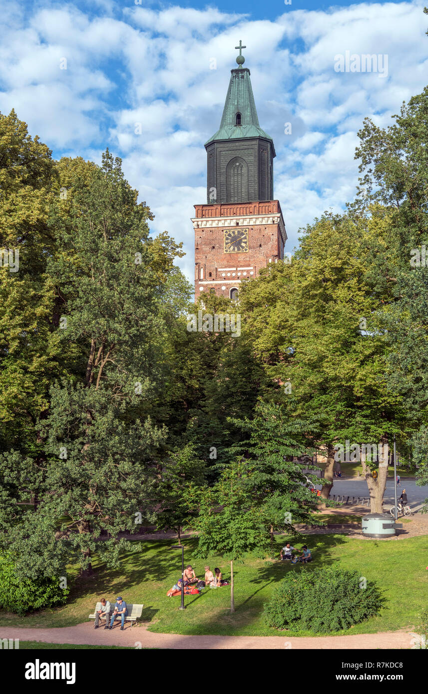 I giovani in seduta Tuomiokirkonpuisto (Cattedrale Park) nella luce del sole serale con la cattedrale di Turku (Turun tuomiokirkko) dietro, Turku, Finlandia Foto Stock