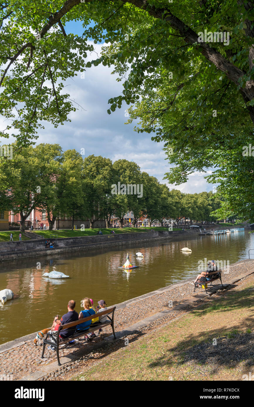 La gente seduta sulle sponde del fiume Aura (Aurajoki) nel centro storico, Turku, Finlandia Foto Stock