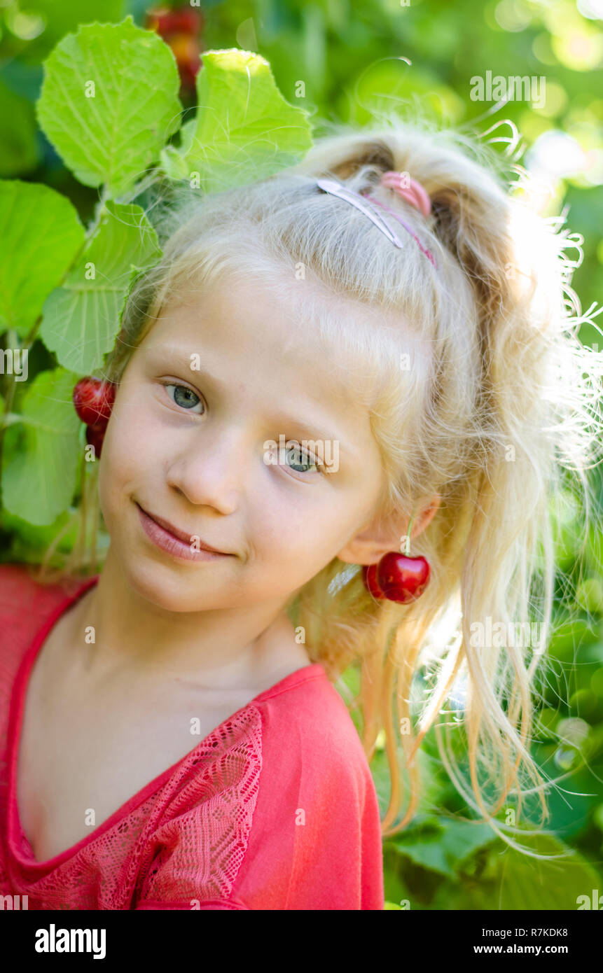 Adorabile ragazza bionda con frutti di ciliegio in orecchie ritratto Foto Stock