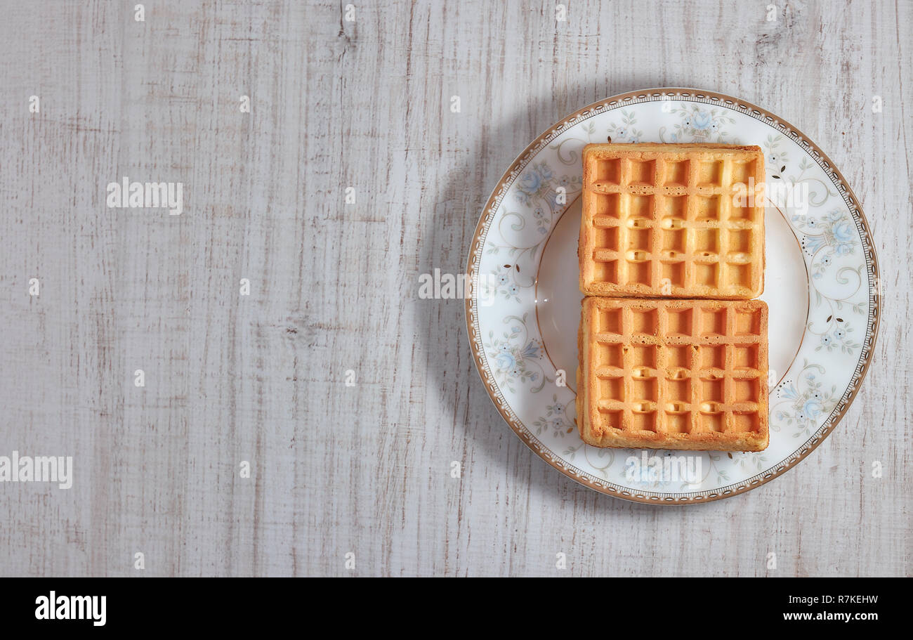 Vista superiore dolce fresco cialde Viennese sulla piastra isolata su un tavolo di legno. copia spazio. Unione per la prima colazione. Foto Stock