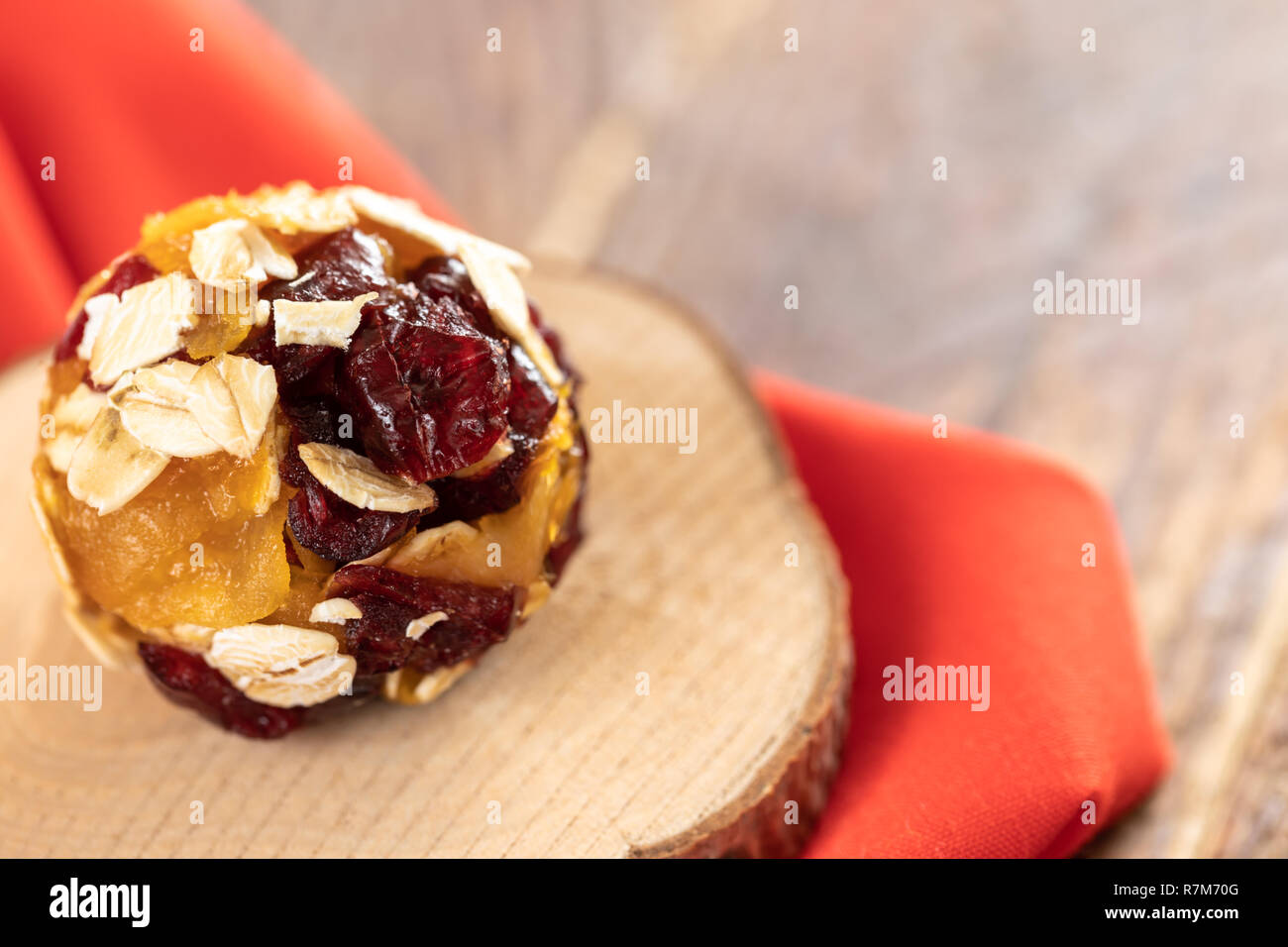 Una energia in casa una sfera realizzata da pezzi di frutta secca su legno taglio sul tessuto rosso. Foto Stock