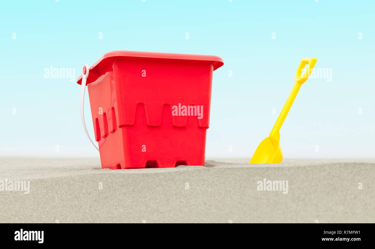 Benna di rosso e di giallo pala in spiaggia di sabbia con il blu del cielo. Foto Stock