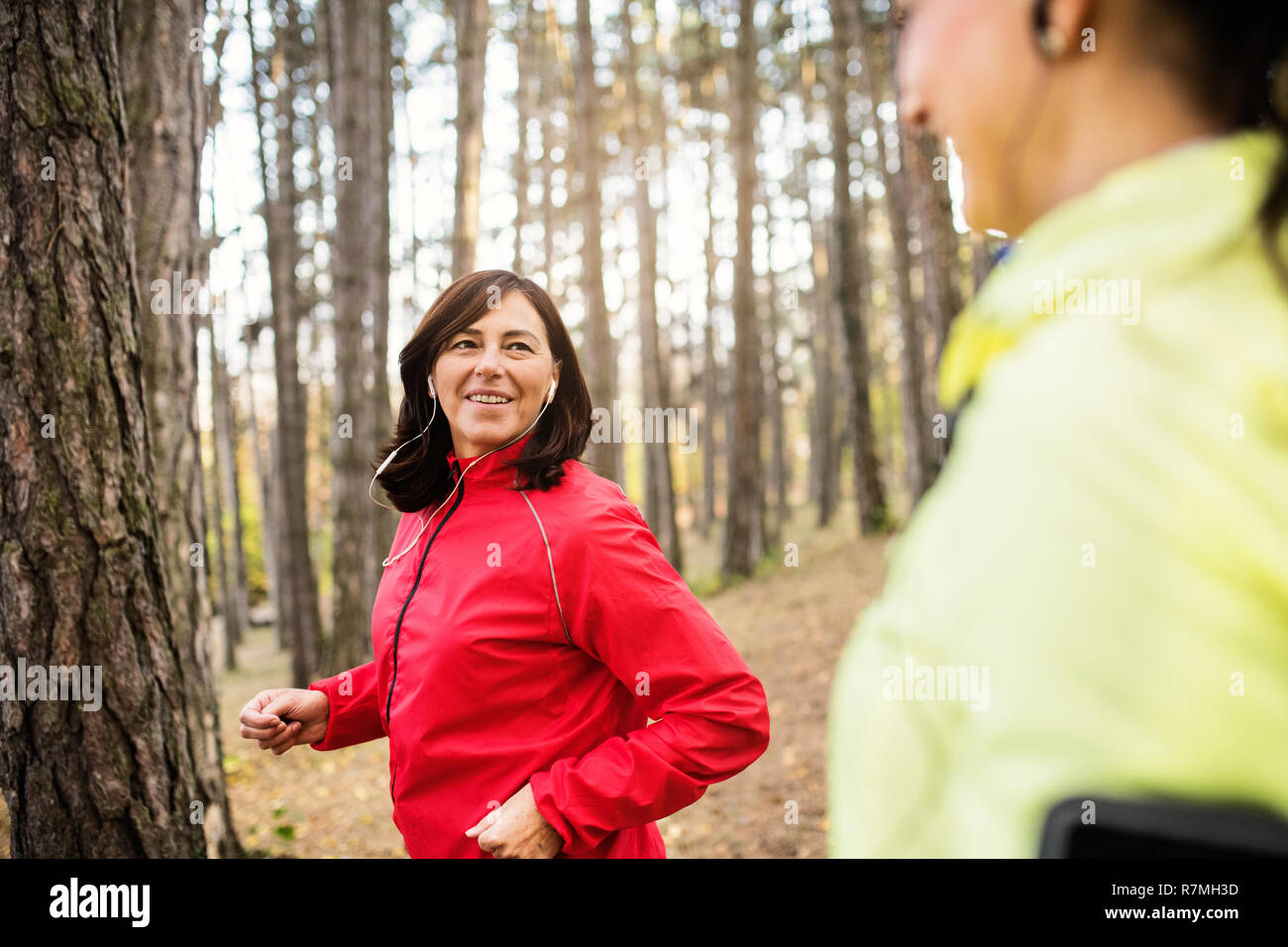 Donna con cuffie jogging all'aperto nella foresta. Foto Stock
