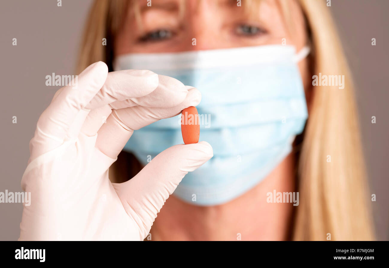 Donna che indossa una maschera tenendo una prescrizione compressa in una mano Foto Stock
