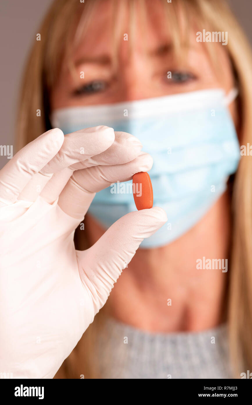 Donna che indossa una maschera tenendo una prescrizione compressa in una mano Foto Stock