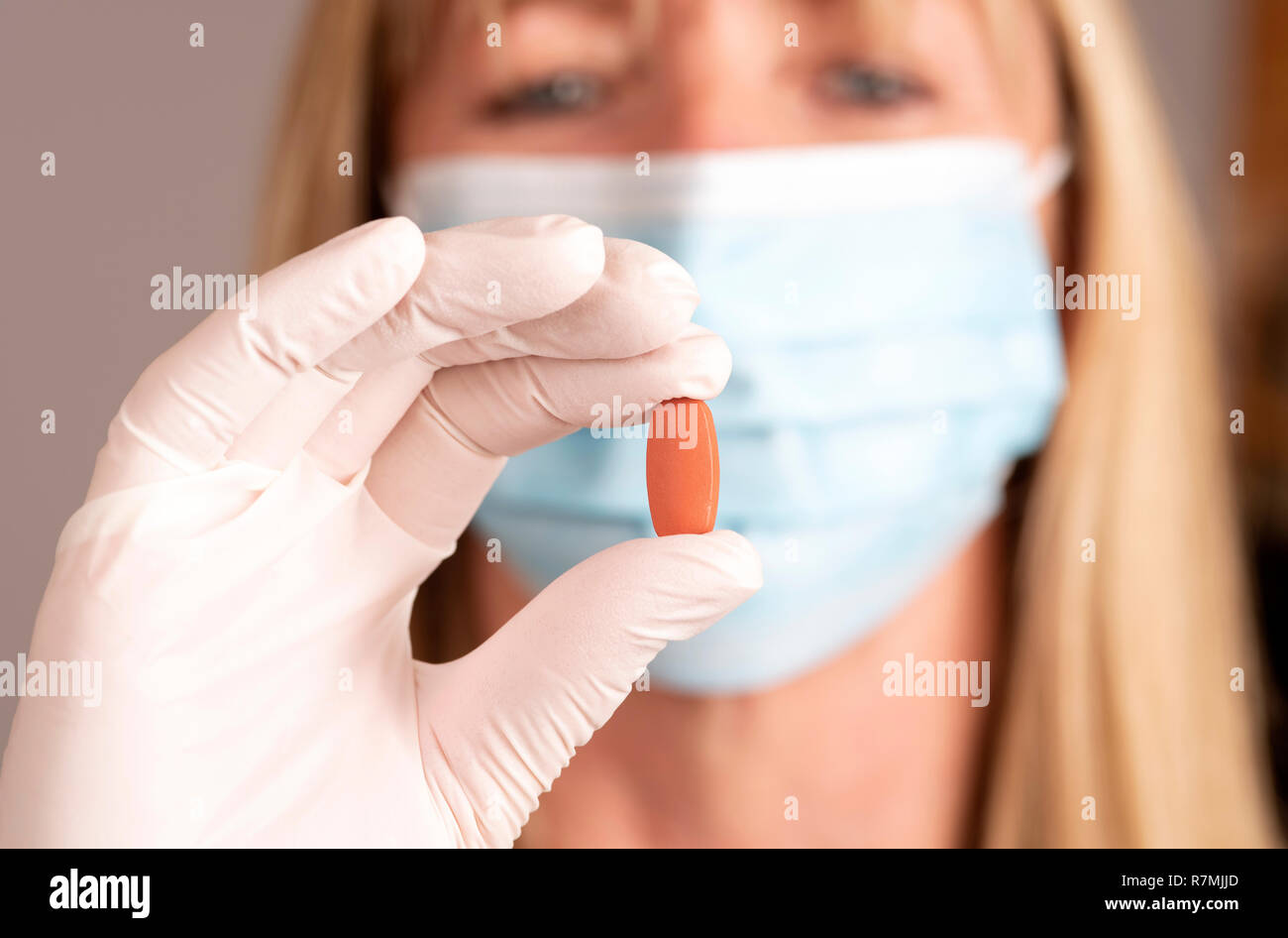 Donna che indossa una maschera tenendo una prescrizione compressa in una mano Foto Stock