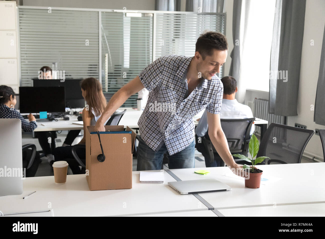 Felice giovane lavoratore di ufficio, intern disimballare belongings workplace Foto Stock