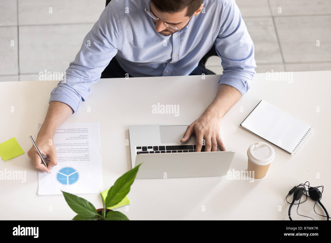 Grave dipendente utilizzando laptop, rendendo note, vista dall'alto Foto Stock