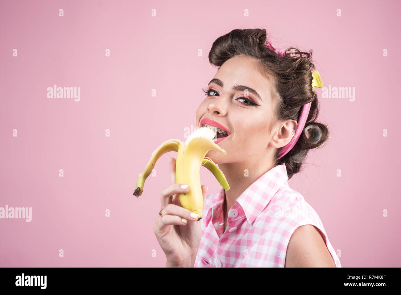 Pinup ragazza con i capelli di moda. pin up donna con il trucco alla moda. banana dieta. retrò donna mangiare banana. Pretty girl in stile vintage, copia dello spazio. Così saporito Foto Stock