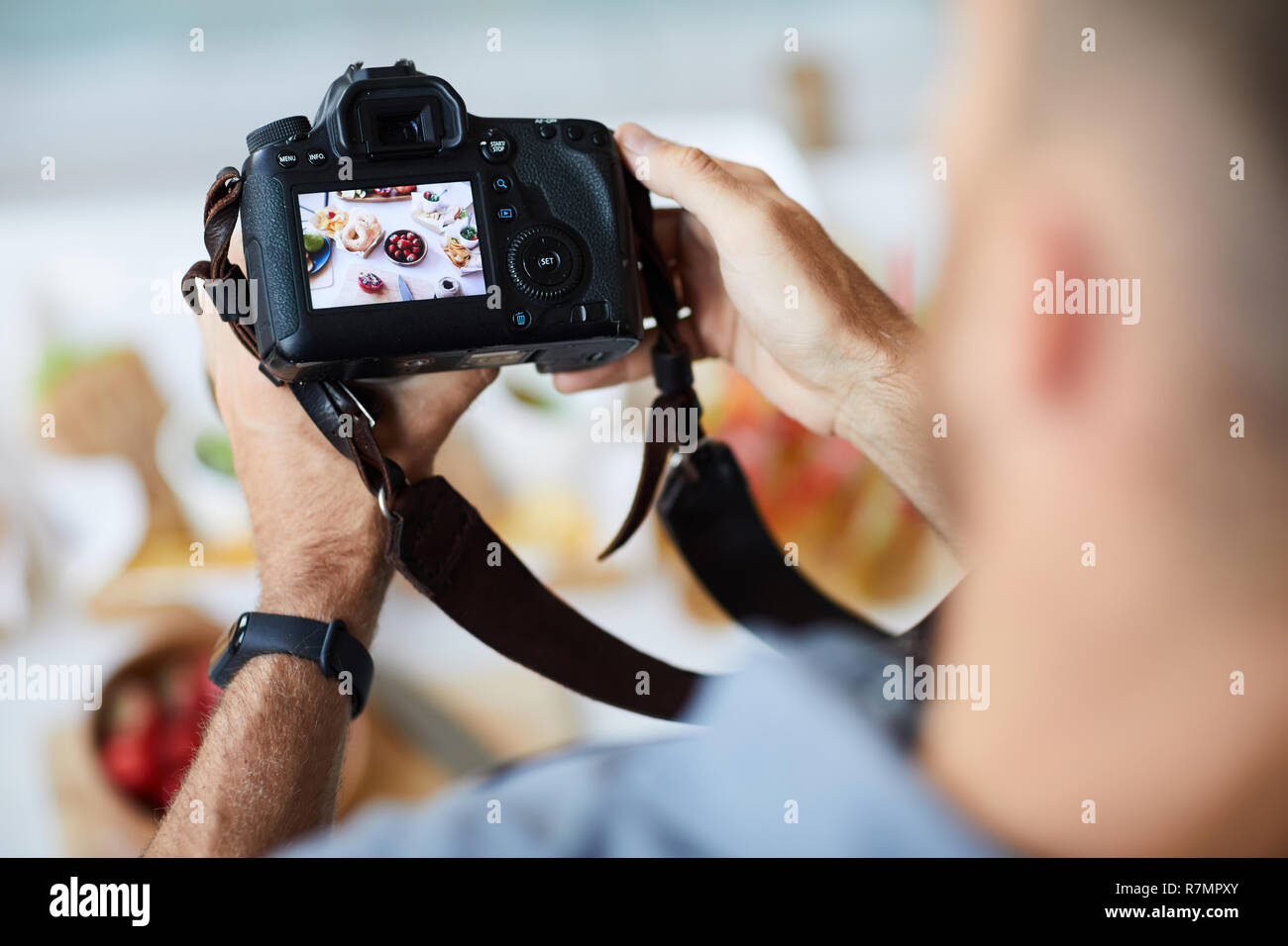 Sopra Visualizza Ingrandimento di un irriconoscibile fotografo azienda professionale di foto mentre la fotocamera per scattare foto di cibo sul tavolo, spazio di copia Foto Stock