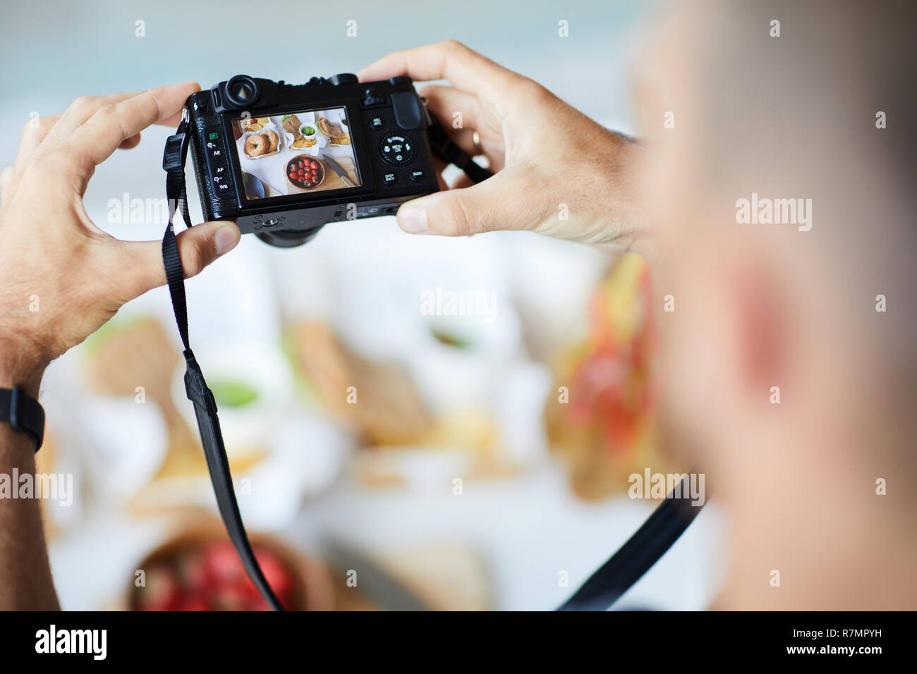Sopra Visualizza Ingrandimento di un irriconoscibile fotografo holding fotocamera digitale durante la ripresa di immagini del cibo sul tavolo, spazio di copia Foto Stock