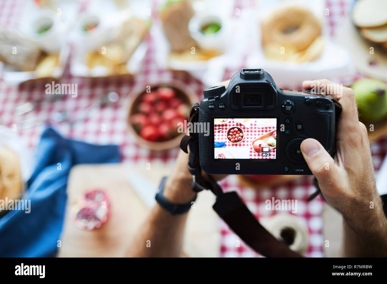 Sopra Visualizza ingrandimento del fotografo tenere la fotocamera quando si scattano fotografie di cibo sul tavolo da picnic, spazio di copia Foto Stock
