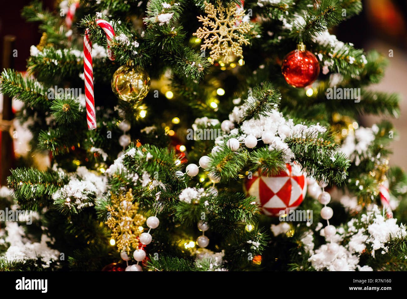 Foto di albero di Natale con palline rosse, caramello canne, dono, golden  fiocchi di neve, primo piano Foto stock - Alamy