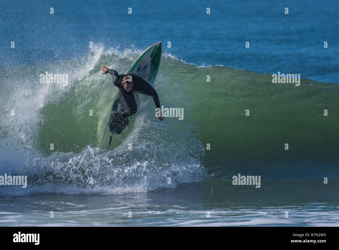 Surfer in nero muta battenti fino la faccia d'onda in un potere spostare durante l'inizio di una grande a nord-ovest si gonfiano in Ventura, California, Stati Uniti d'America su dicembre Foto Stock
