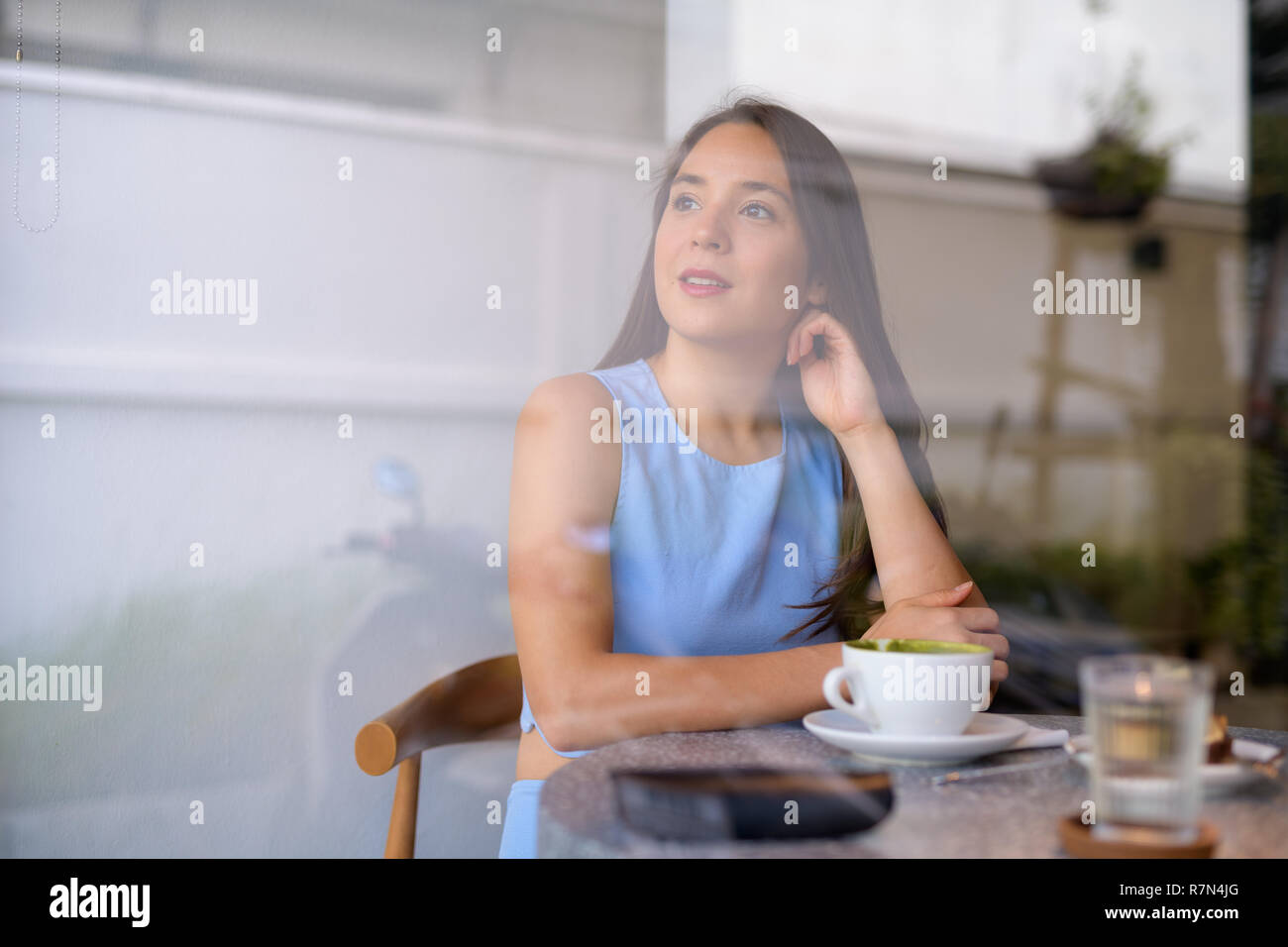 Bella giovane imprenditrice pensare guardando attraverso la finestra al coffee shop Foto Stock