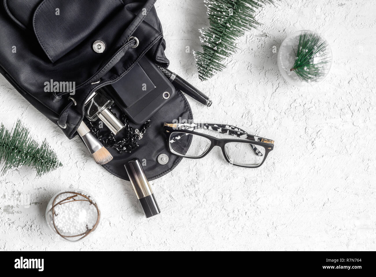 Buon Natale e Felice newyear Bellezza e moda concetto. Lay piatto di Natale ornamenti e nero donna aperto il sacchetto con accessori, smartphon Foto Stock