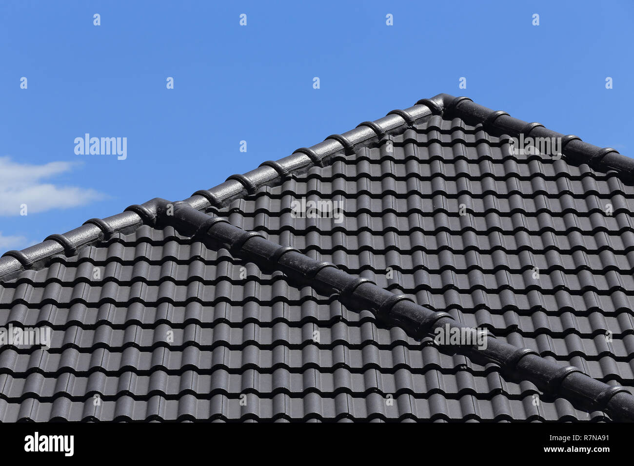 Piastrelle nere sul tetto di una casa nuova con cielo blu Foto Stock