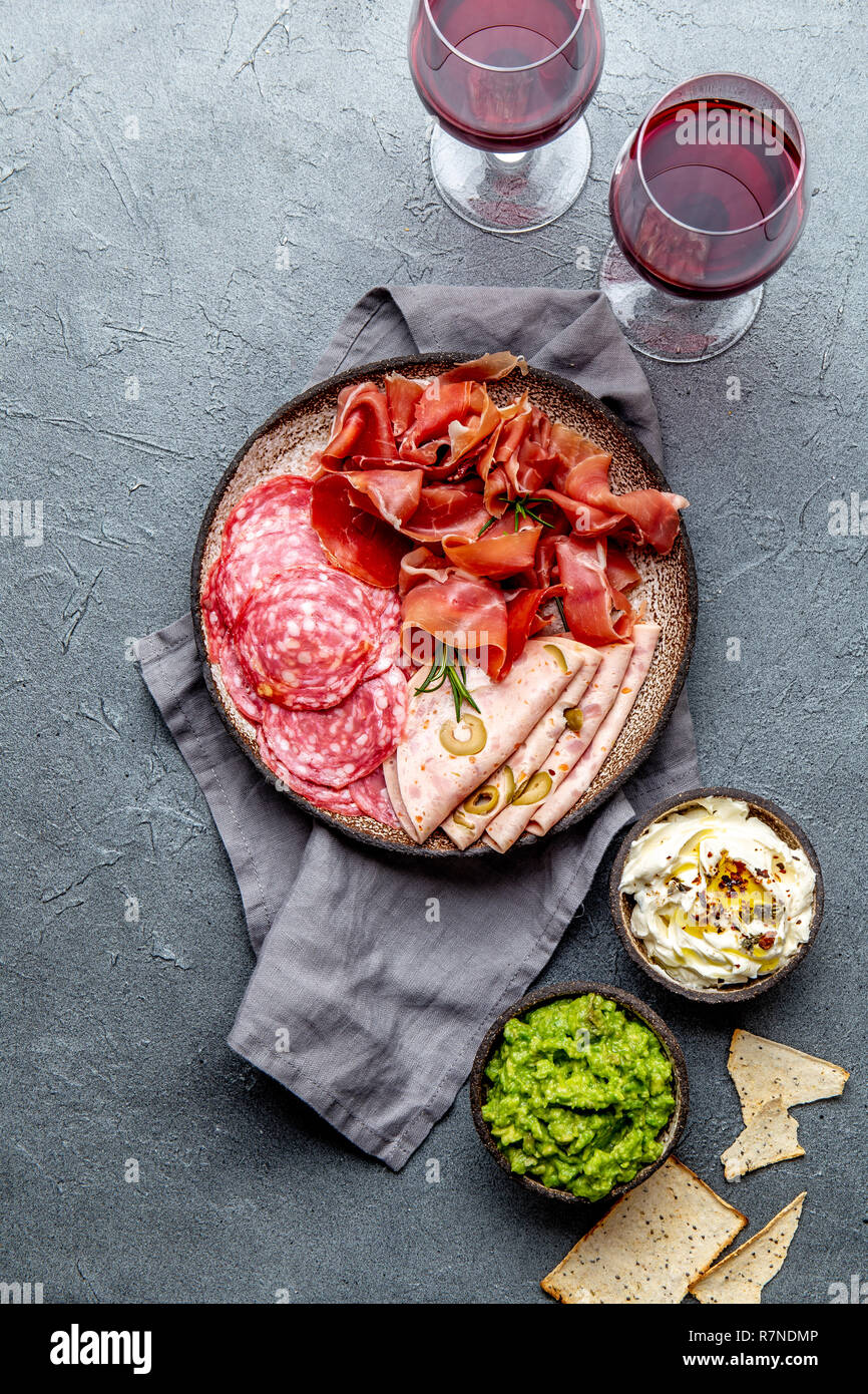 Antipasto. Piatto a base di carne, patatine e salse, vino rosso su sfondo grigio. Vista superiore Foto Stock