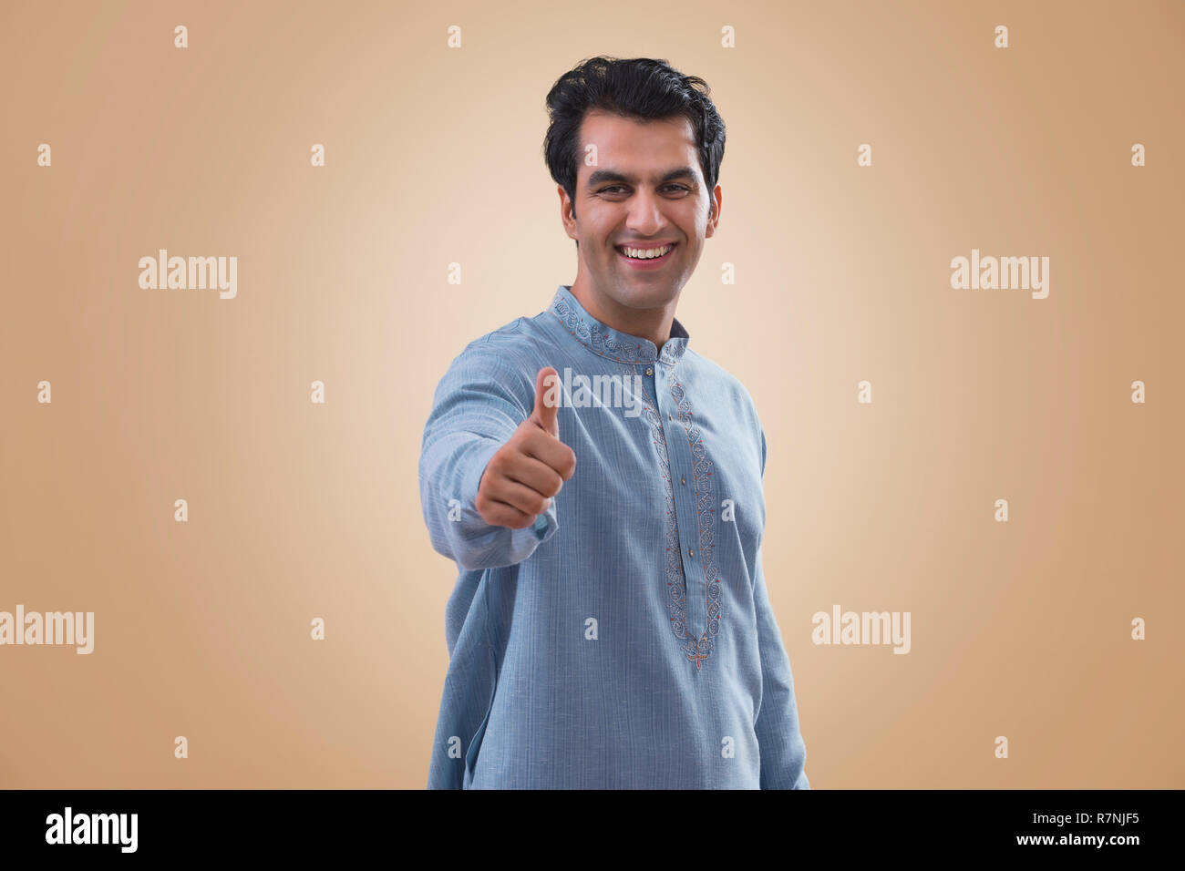 Ritratto di un sorridente giovane uomo che mostra pollice in alto segno. Foto Stock