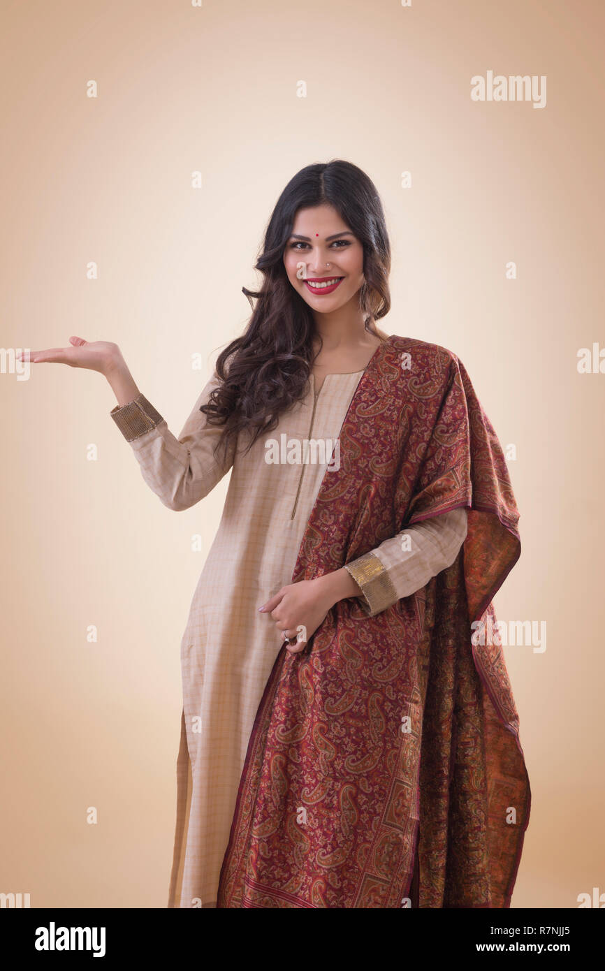 Ritratto di un sorridente giovane donna in abito tradizionale mostra aprire Palm. Foto Stock