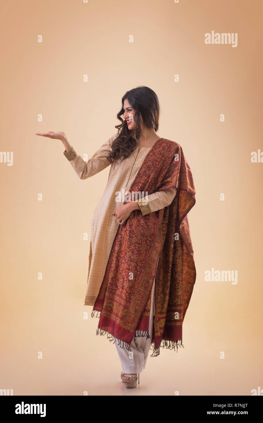 Ritratto di un sorridente giovane donna in abito tradizionale mostra aprire palm e lo sta guardando. Foto Stock