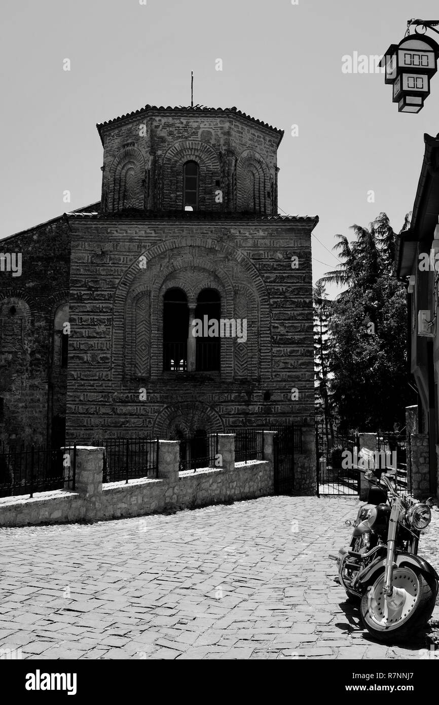 Visualizzazione monocromatica di medievale di contrasto la chiesa di Santa Sofia, Ohrid Macedonia e splendente nuova Harley Davison in moto di fronte ad esso in strada di ciottoli Foto Stock
