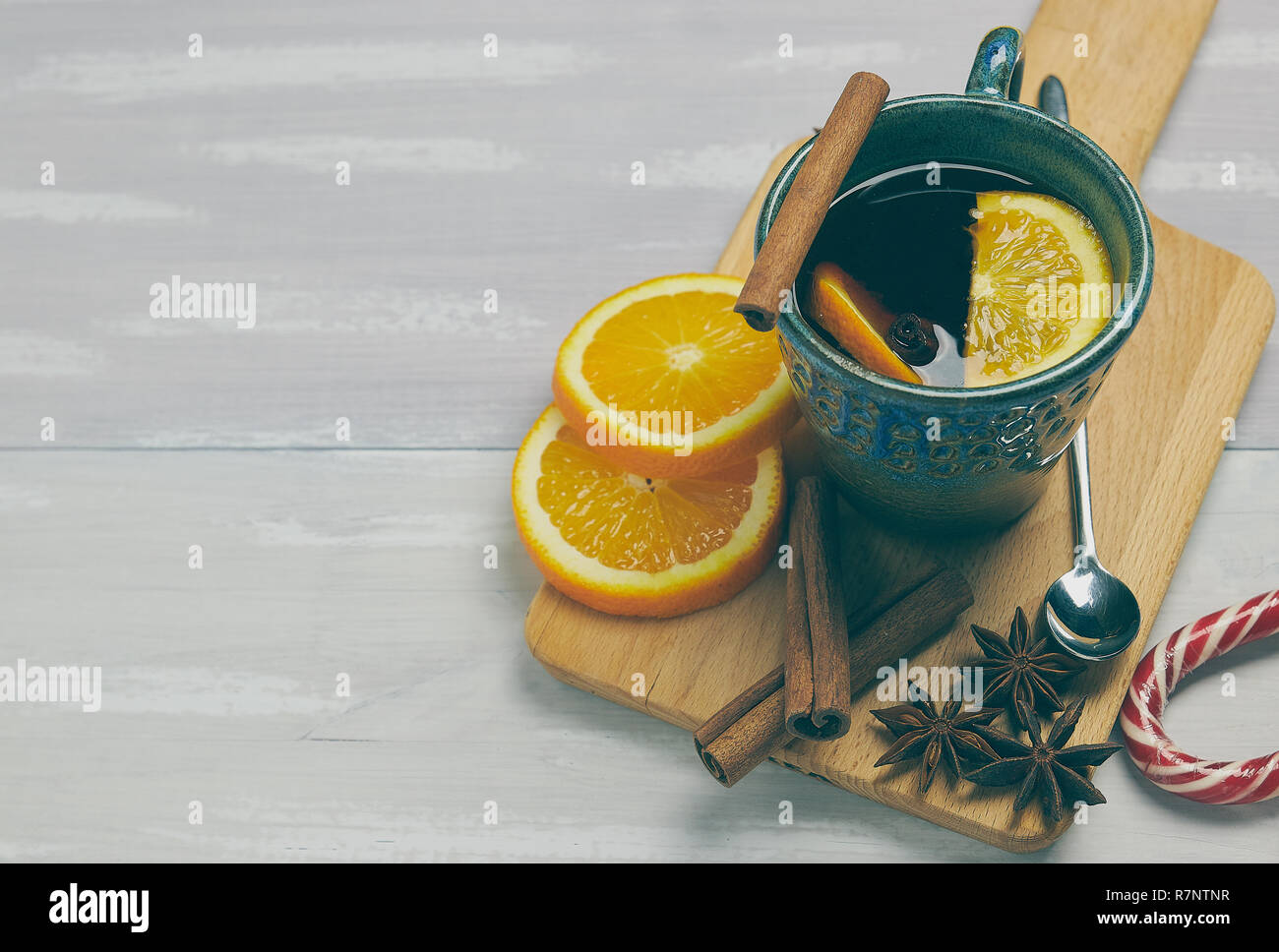 Una tazza di ceramica di riscaldamento tè con cannella e arancio su un rustico tavolo bianco. copia spazio. vista verticale .. Foto Stock