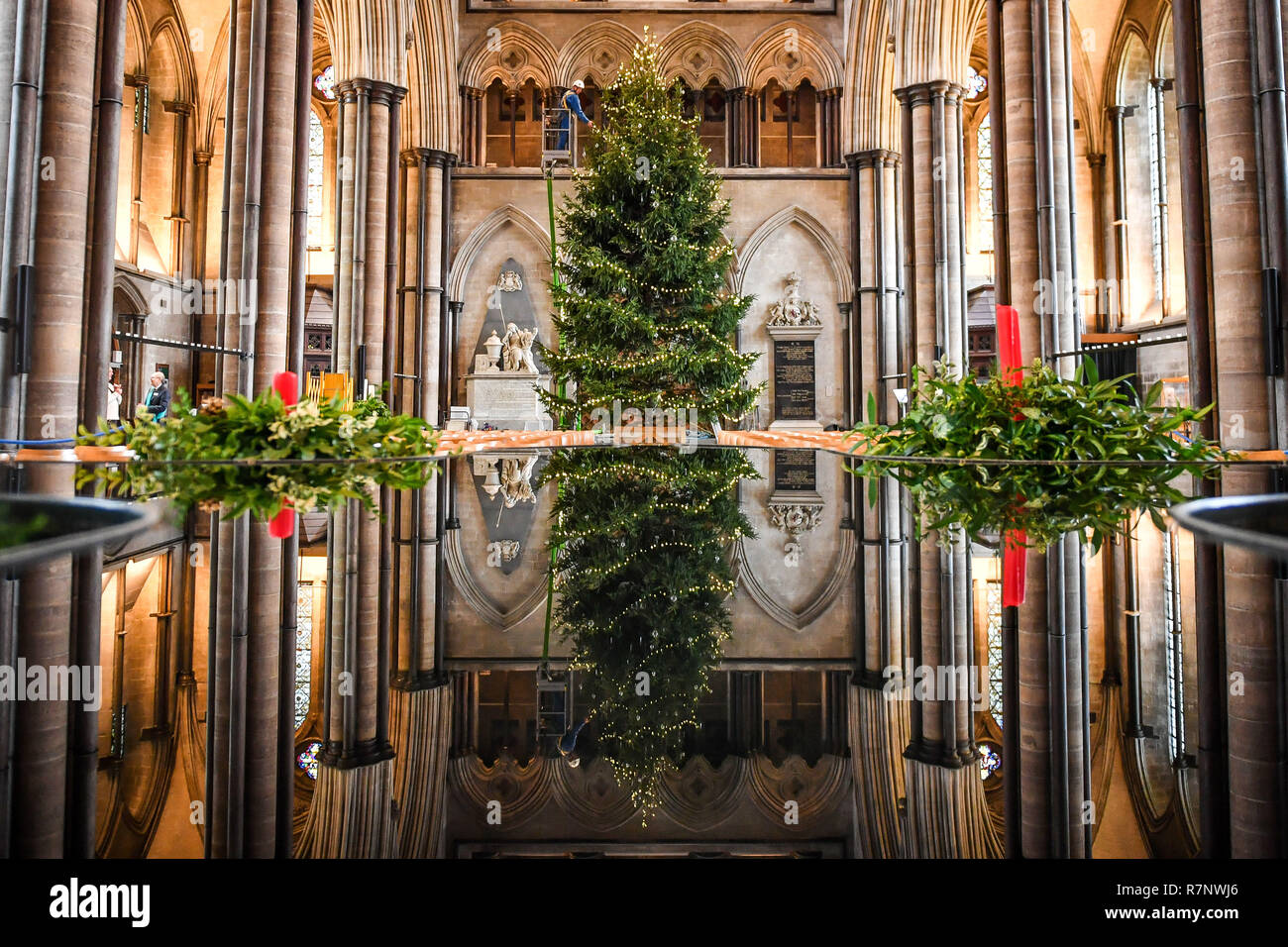 La Cattedrale di Salisbury ecclesiastiche di falegname, Richard Pike decora il 34ft Abete rosso albero di Natale, abbattuto a Longleat Estate, come il finale di rifili, compresi 1000 luci LED, baubles di vetro e gocce di ghiaccio, sono disposte sull'albero, che sta di fronte alla finestra Occidentale. Foto Stock