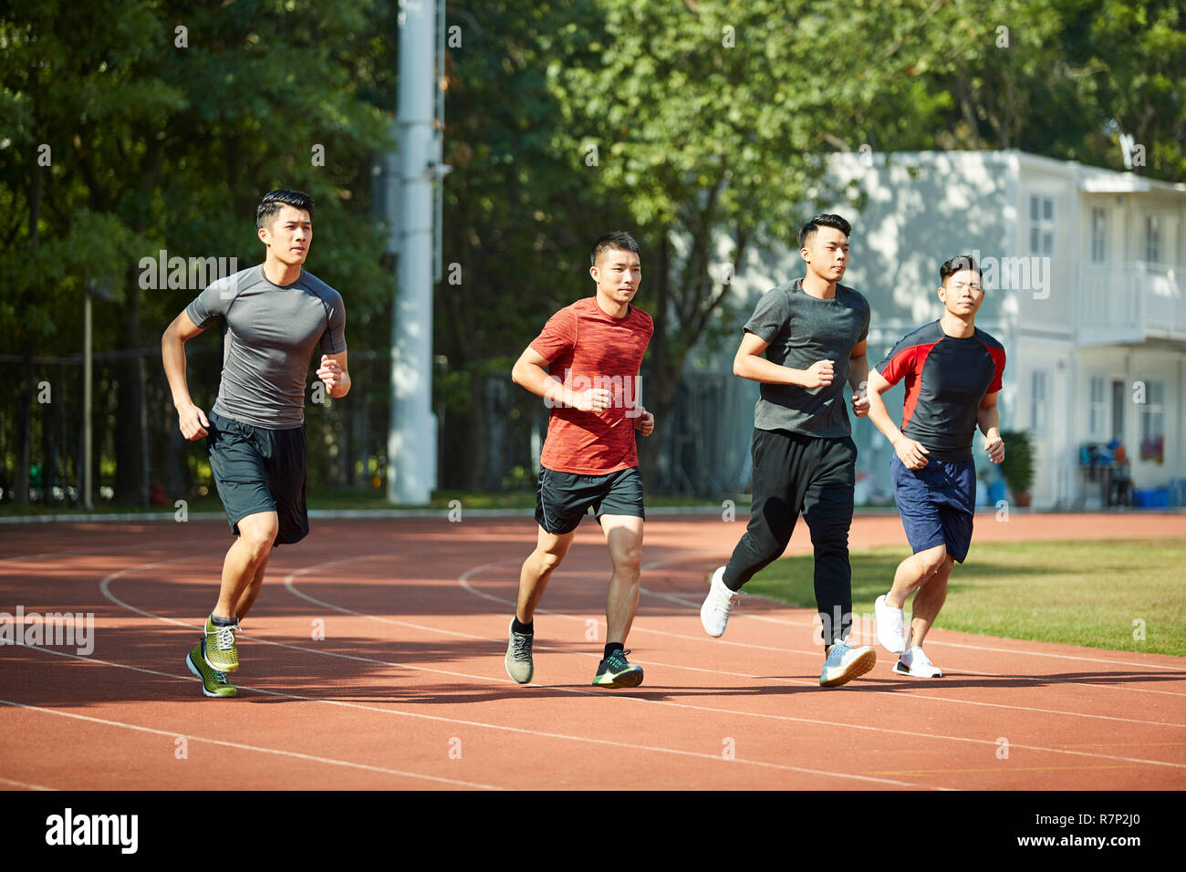 Un gruppo di quattro giovani atleti asiatici training su pista. Foto Stock