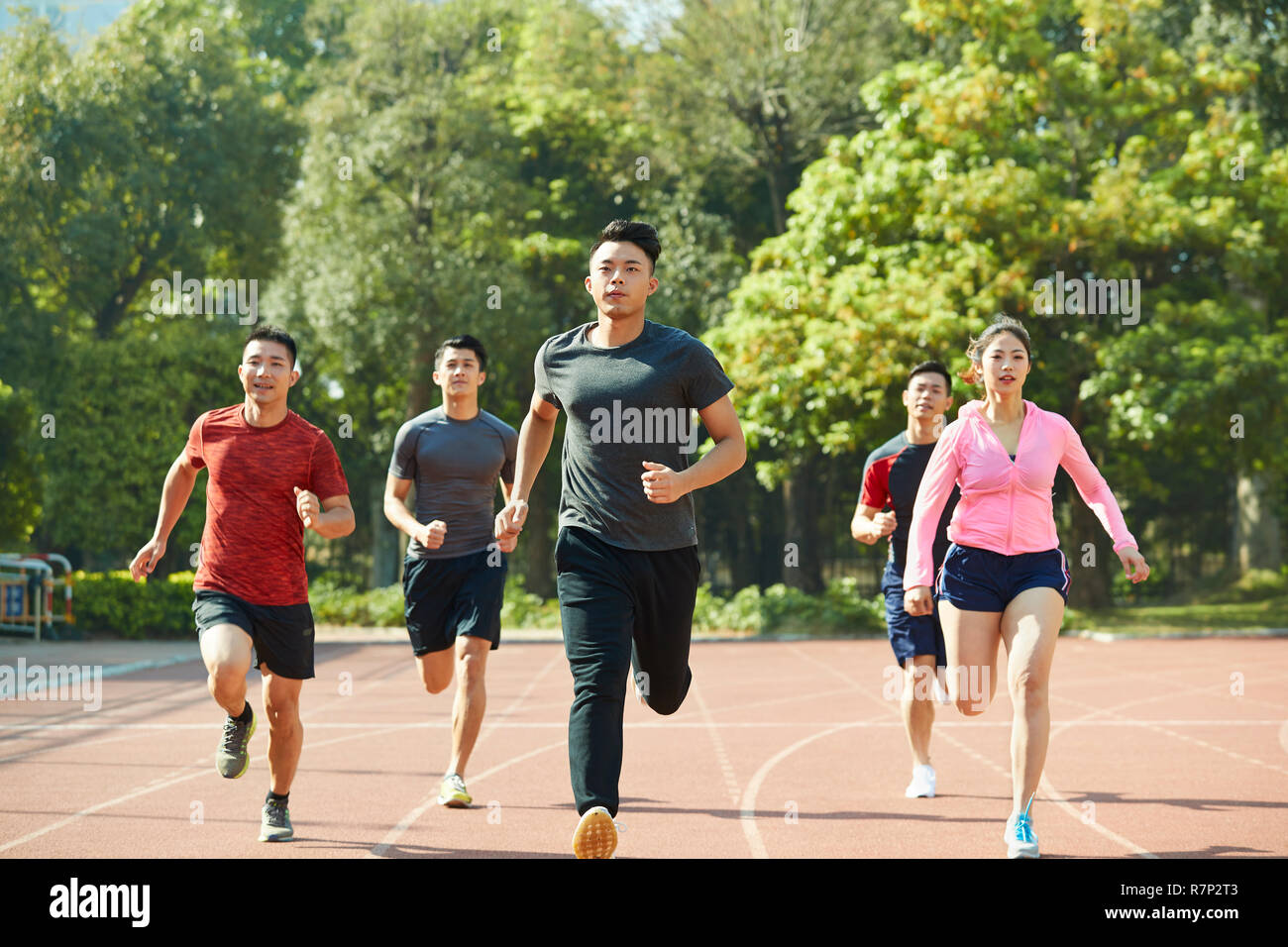 Un gruppo di giovani atleti asiatici maschio e femmina insieme di formazione sulla via. Foto Stock
