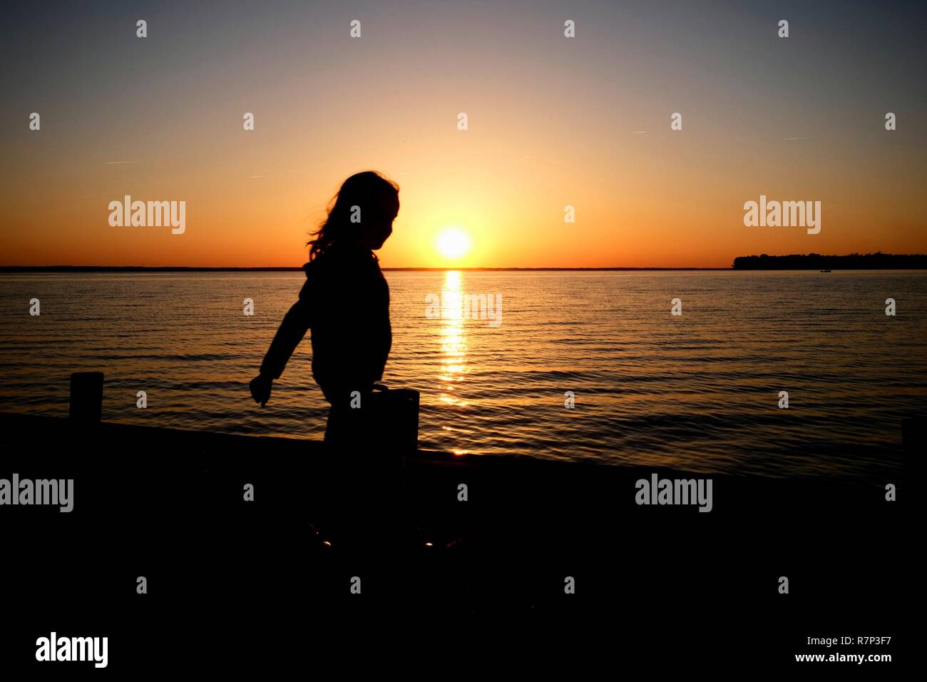 Profilarsi di una bambina camminano sul molo durante il tramonto al Neuse estuario del fiume in un parco in Arapahoe North Carolina. Foto Stock